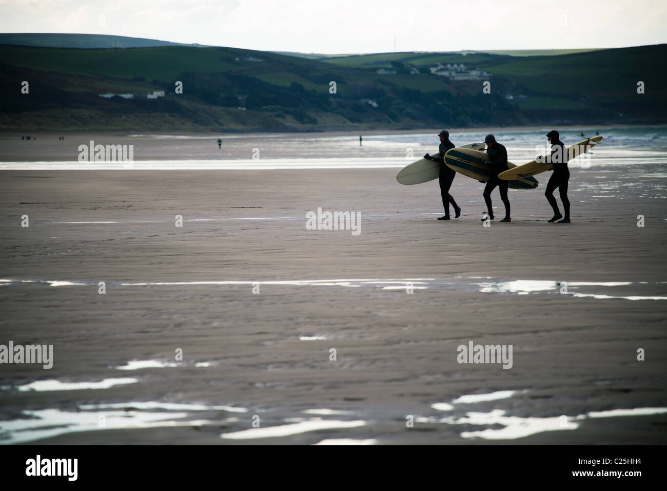 Drei unbekannte Surfer zu Fuß hinauf einen Strand (Woolacombe, Devon) Stockfoto