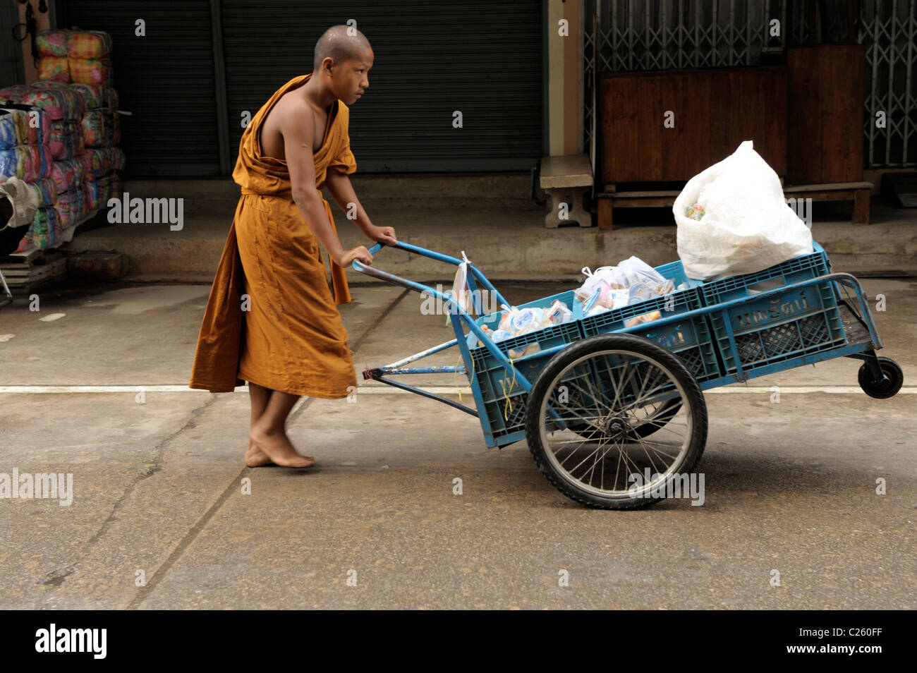 junge Novize Schieben Karren mit Lebensmitteln sammeln am Morgen Almosen rund, Mae Sot, Nord-thailand Stockfoto