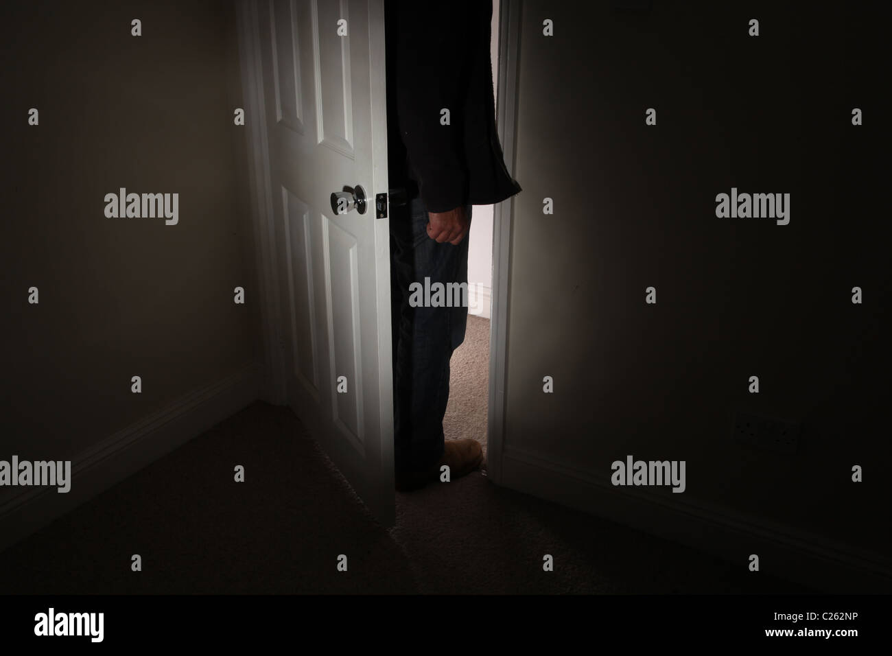 Schattenhafte Gestalt eines Mannes durch eine Tür führt zu einem dunklen Raum stehen Stockfoto