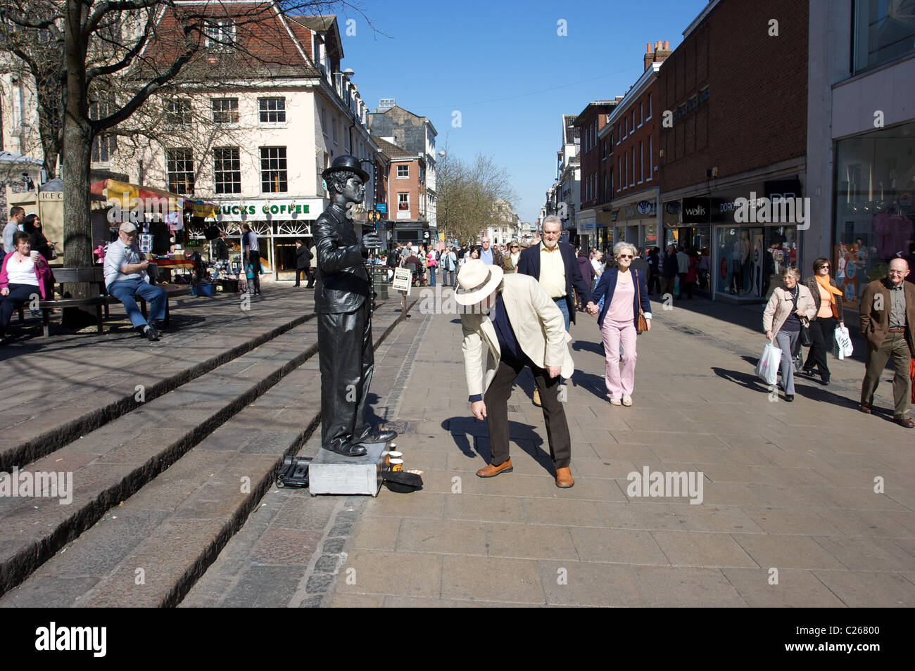 ein Mann geben Geld für Charlie Chaplin, Straßenmusik in Norwich, dunkle Statue, Norfolk, Großbritannien Stockfoto