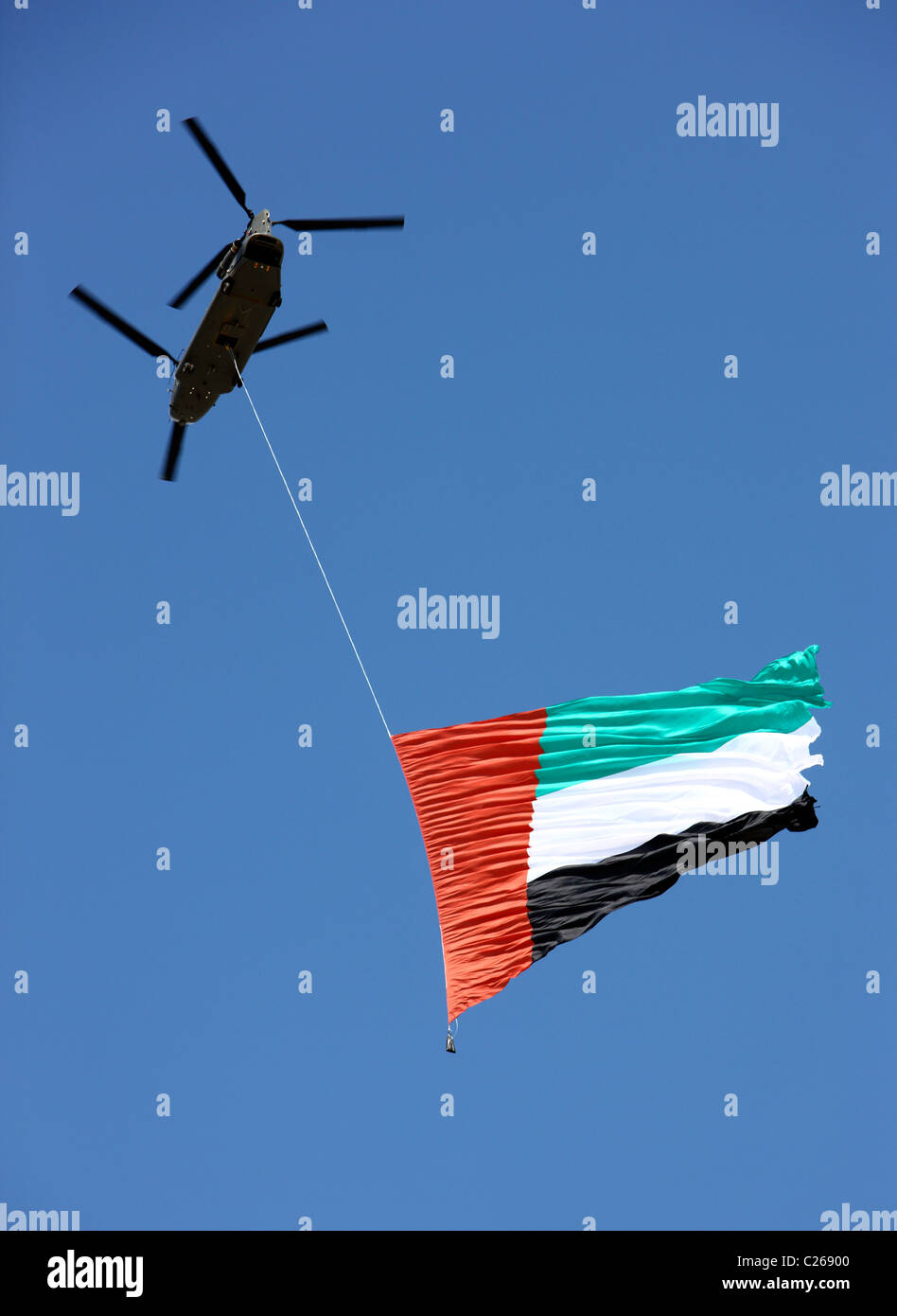 Militärhubschrauber trägt die Flagge der Vereinigten Arabischen Emirate über der Hauptstadt Abu Dhabi. Während einer militärischen Show. Stockfoto