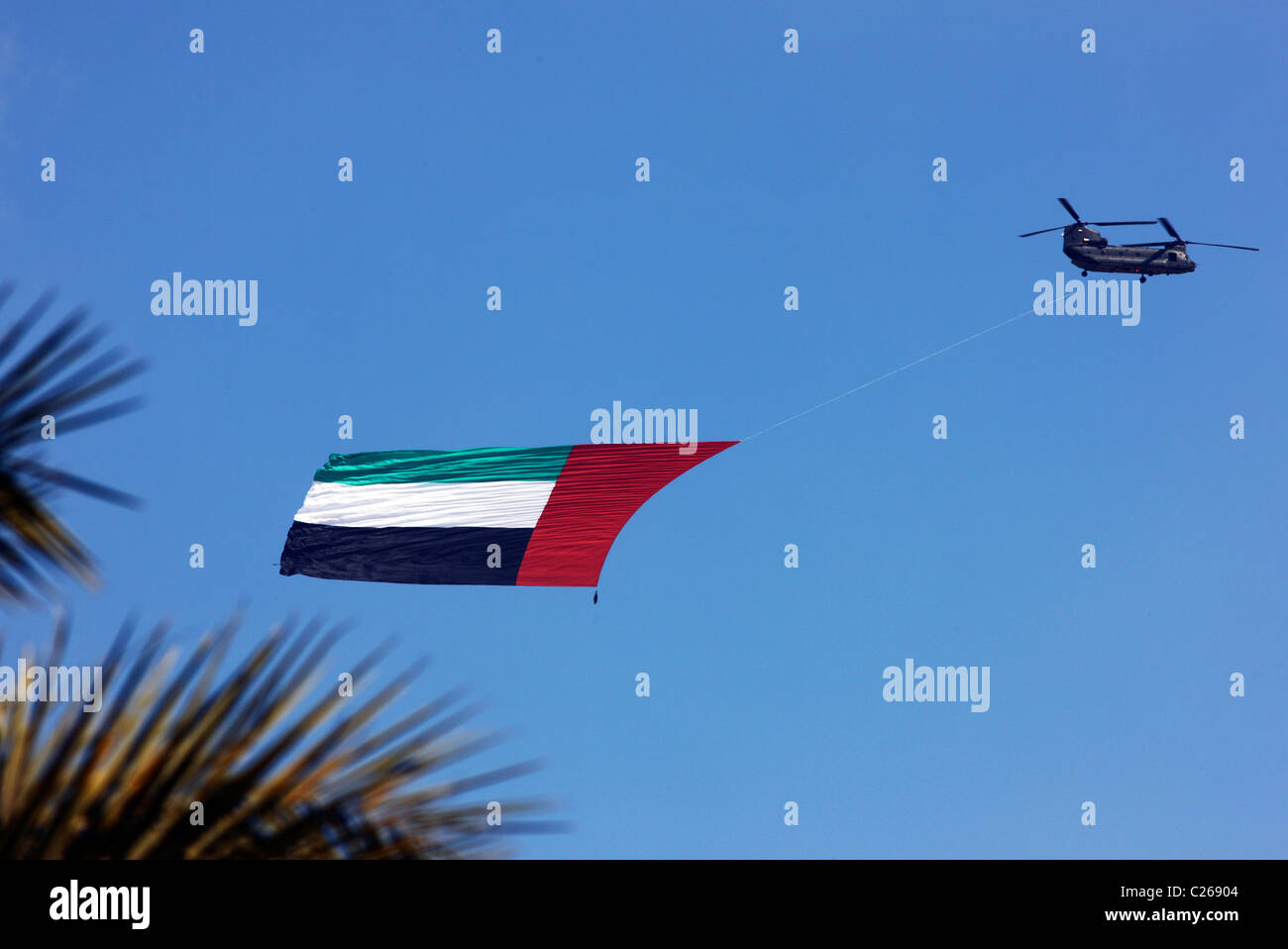 Militärhubschrauber trägt die Flagge der Vereinigten Arabischen Emirate über der Hauptstadt Abu Dhabi. Während einer militärischen Show. Stockfoto
