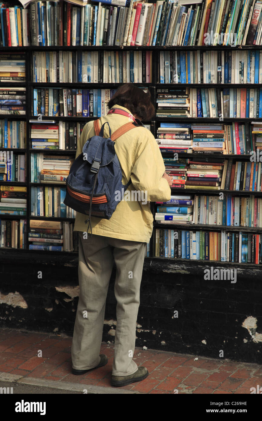 Eine Frau, die Durchsicht der Buchregale außerhalb ein Secondhand-Buchladen in Eastbourne, East Sussex, England. Stockfoto