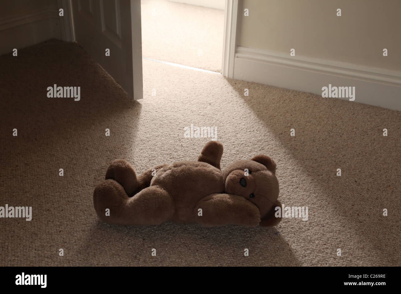 Ein Teddy auf dem Boden durch eine offene Tür. Stockfoto