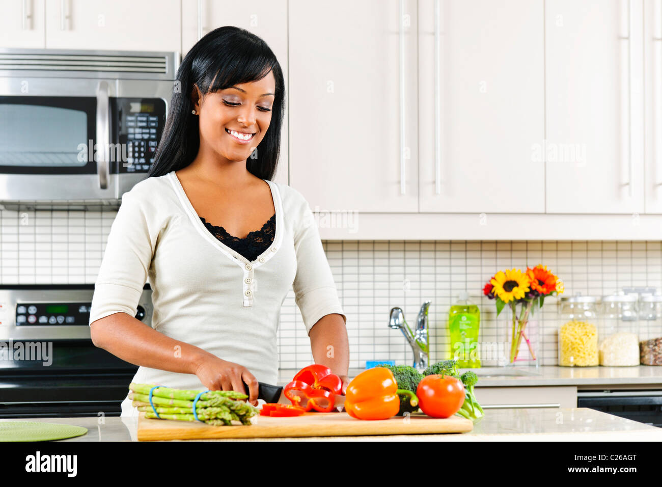 Lächelnde schwarze Frau Schneiden von Gemüse in der modernen Küche Interieur Stockfoto