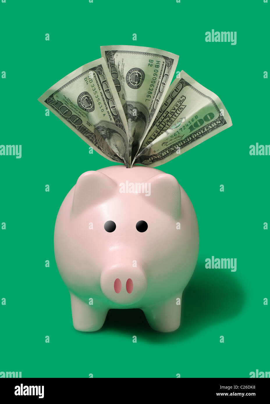 Sparschwein isoliert auf grünem Hintergrund mit hundert Dollar Scheinen Überfüllt Stockfoto