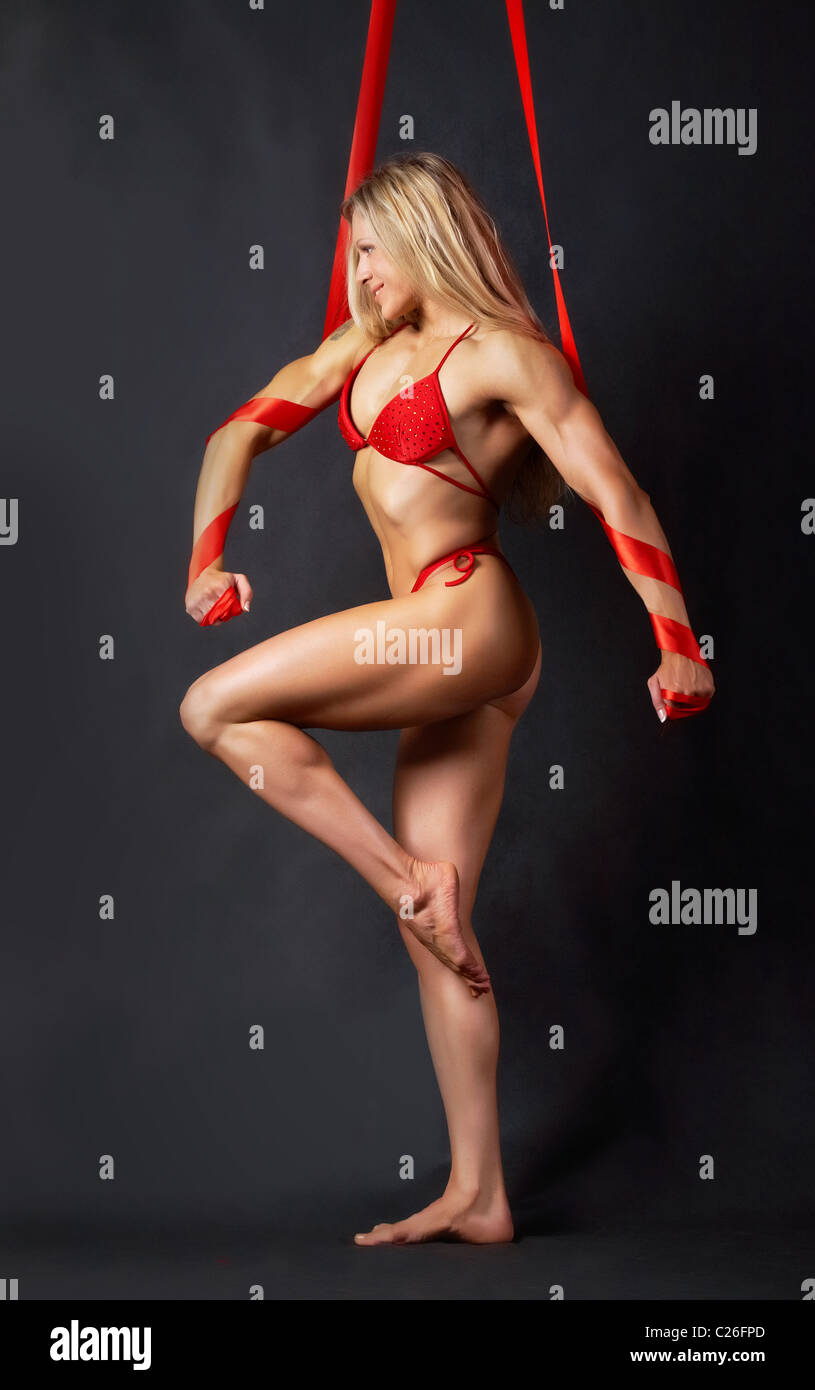 Ein schönes Modell im roten Bikini marschieren auf der linken Seite mit roten Bändern gewickelt runden ihre Arme Stockfoto