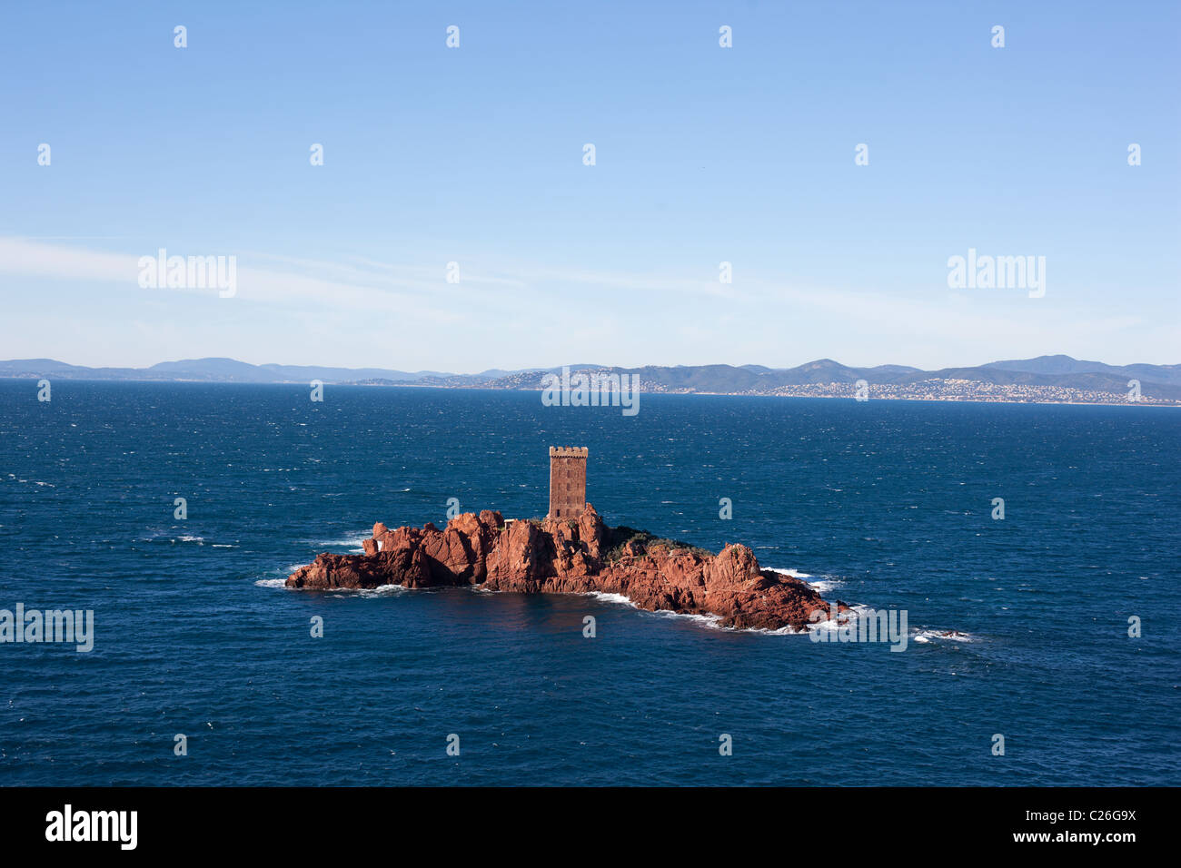 Kleine Insel mit atemberaubendem rotem vulkanischem Gestein, gekrönt von einem quadratischen Turm der gleichen Farbe. L'Île d'Or, Esterel Massif, Saint-Raphaël, Var, Frankreich. Stockfoto