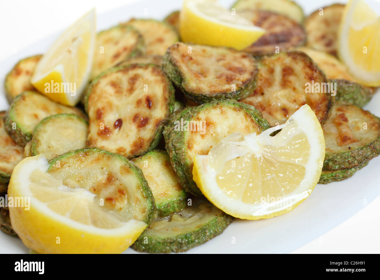 Nahaufnahme von einem Teller mit gebratenen Zucchini (Zucchini) Ringe auf einem Teller mit Zitronenvierteln Stockfoto