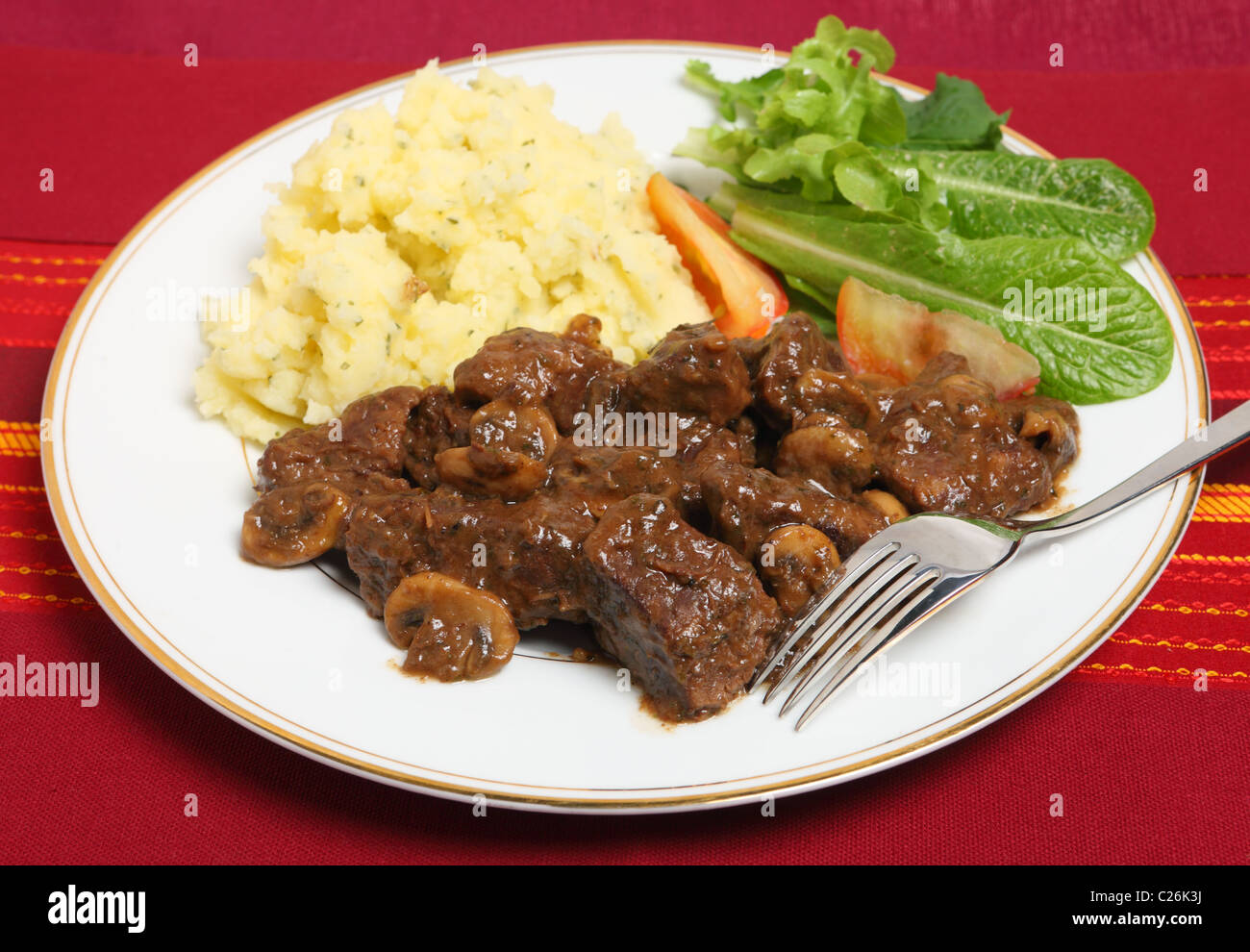 Beef Bourguignon - Rindfleisch in einer Weinsauce geschmort und mit gebratenen Pilzen - mit Petersilienkartoffeln und Salat Stockfoto