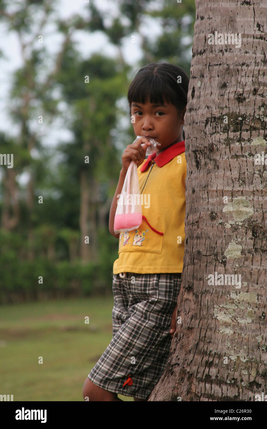 Balinesische Mädchen mit einem rosa Getränk in die Kamera schaut. Stockfoto