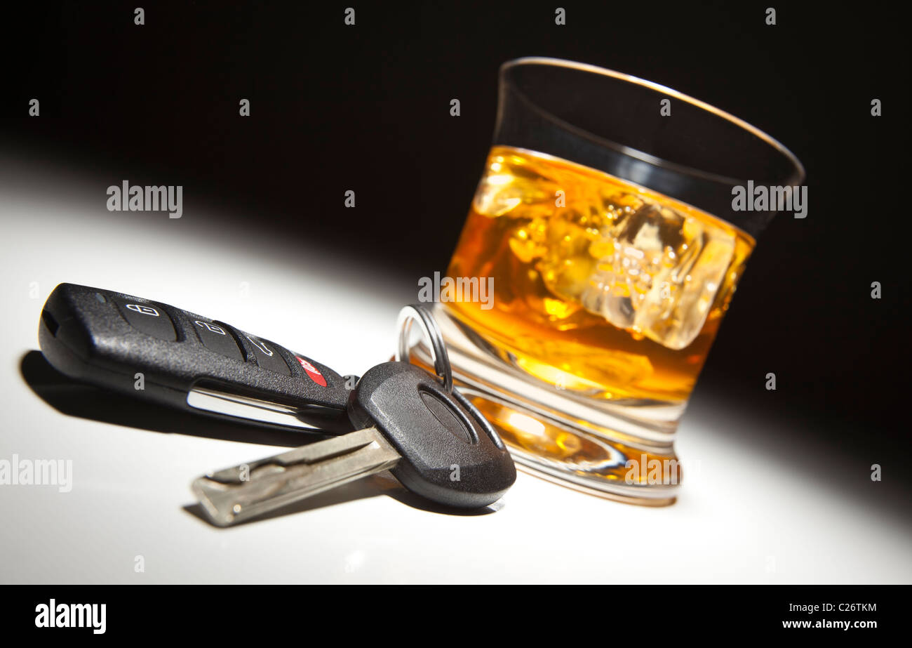 Alkoholisches Getränk und Autoschlüssel unter Spot-Licht. Stockfoto