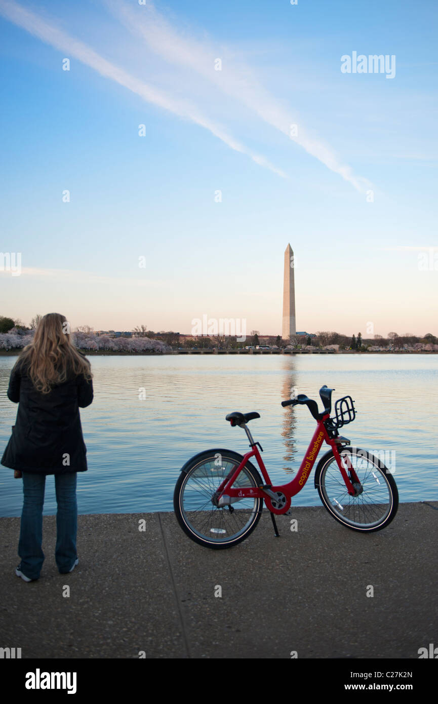 Washington DC eine junge Dame mit dem Fahrrad in den Vordergrund und Kirsche blüht und das Washington Monument im Hintergrund Stockfoto