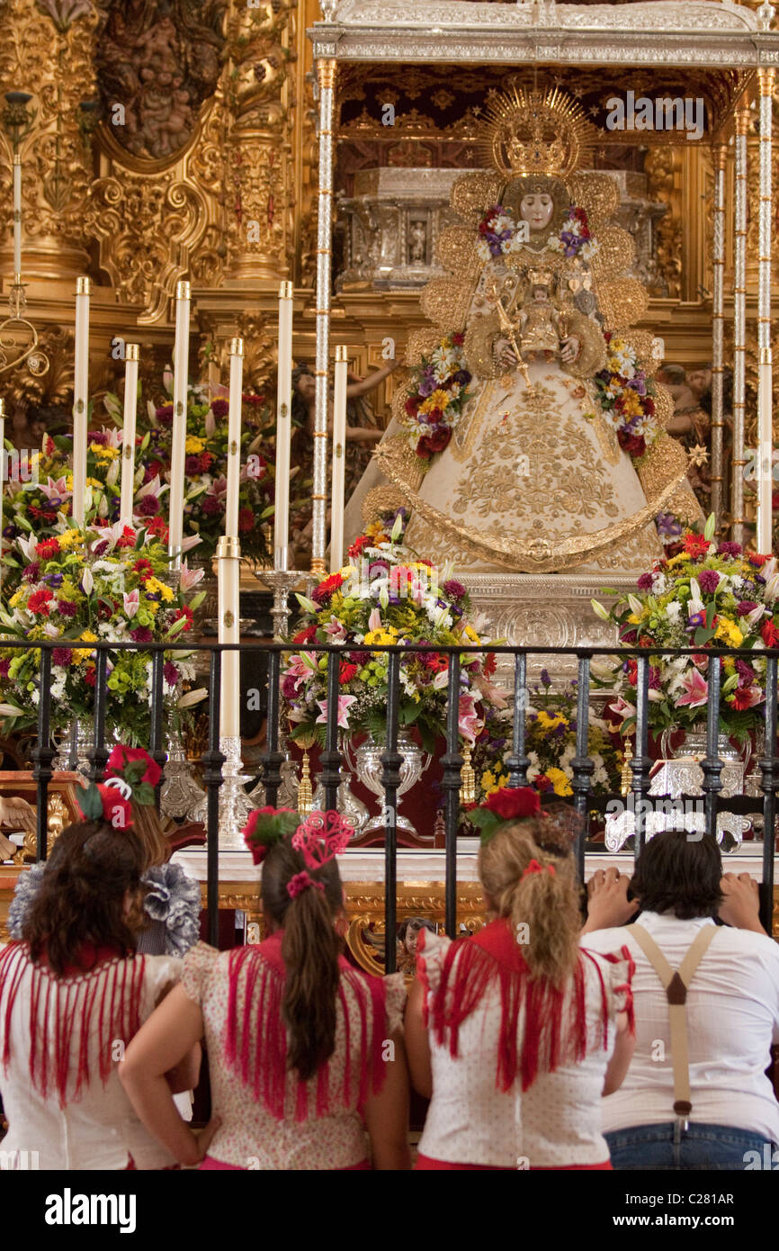 Katholische Pilger vor der Jungfrau von El Rocio innerhalb des Heiligtums in El Rocio, während die Romeria kniend. Stockfoto