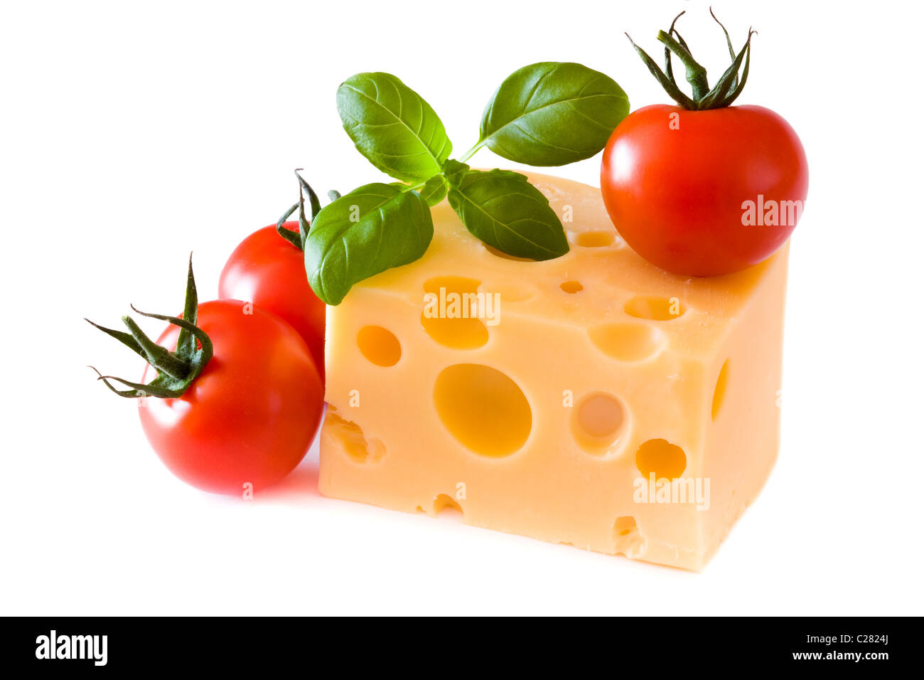 Gelben Käse mit Tomaten und grünen Basilikum isoliert auf weißem Hintergrund Stockfoto