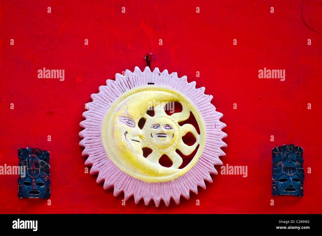 Roten Stuck Wand mit Mond-Sonne und zwei Maya-Maske-Dekorationen an einem Gebäude in Isla Mujeres (Spanisch für Frauen-Insel) Mexiko Stockfoto