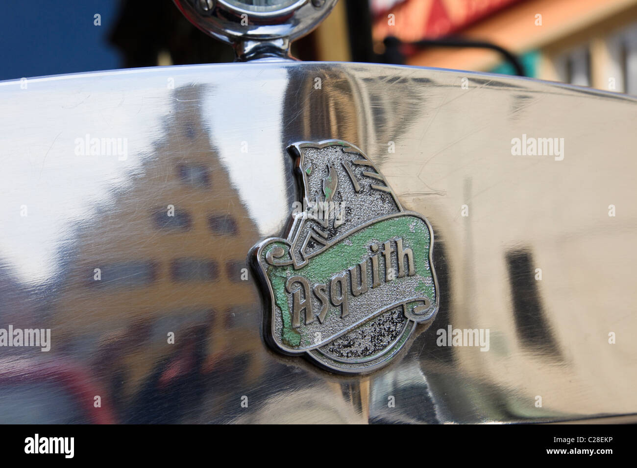 Maker Abzeichen auf der Motorhaube eines alten Asquith Oldtimer Autos mit mittelalterlichen Bauwerken spiegelt sich in der chromework Stockfoto