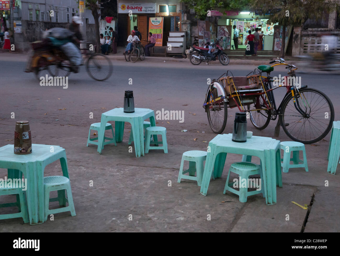 Tee-Shop und Fahrradrikschas in der Abenddämmerung in den Straßen von Mandalay. Myanmar Stockfoto