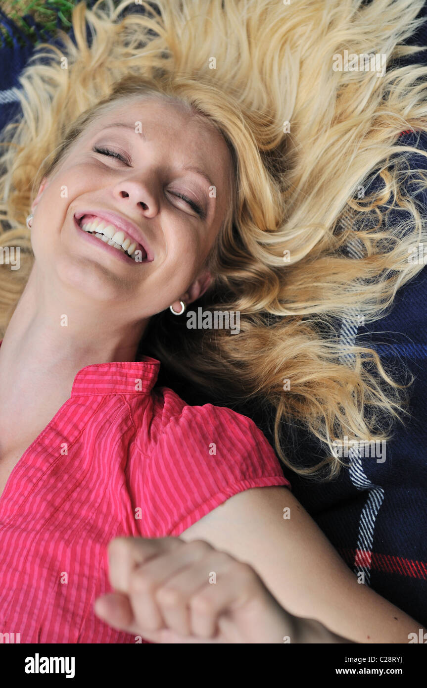Junge, blonde Frau liegend auf Teppich und sehr viel Lachen Stockfoto
