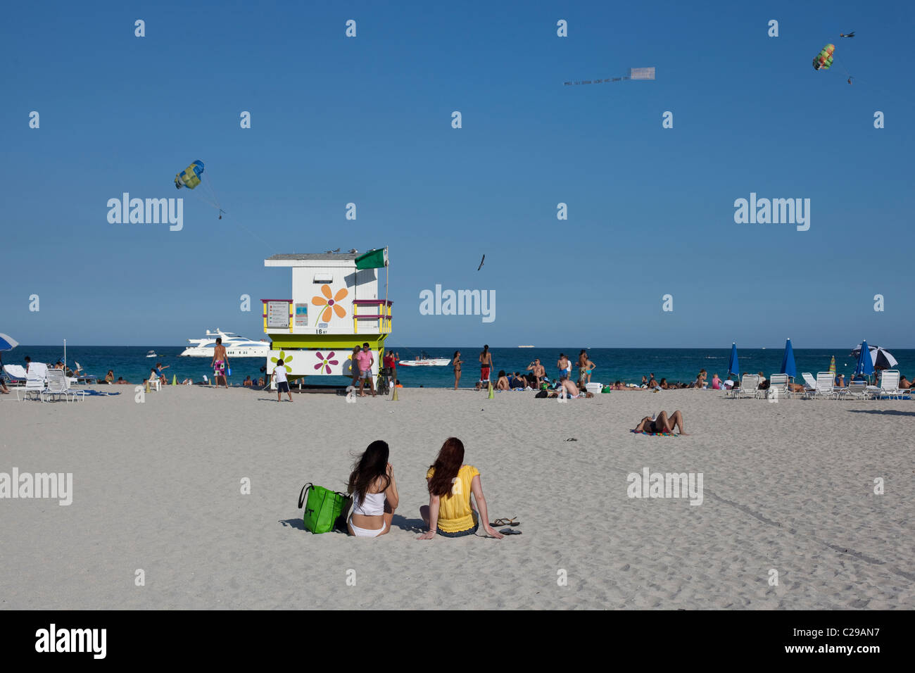 Zwei Mädchen beobachten die Drachen fliegen über das Meer von Miami Beach, FL. Stockfoto