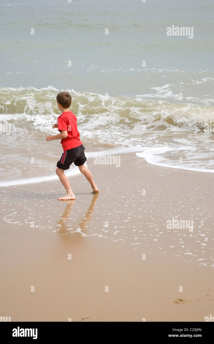 Jungen spielen am Ufer Meeres, die ankommenden Flutwellen auszuweichen. Meer Palling, Norfolk. Stockfoto