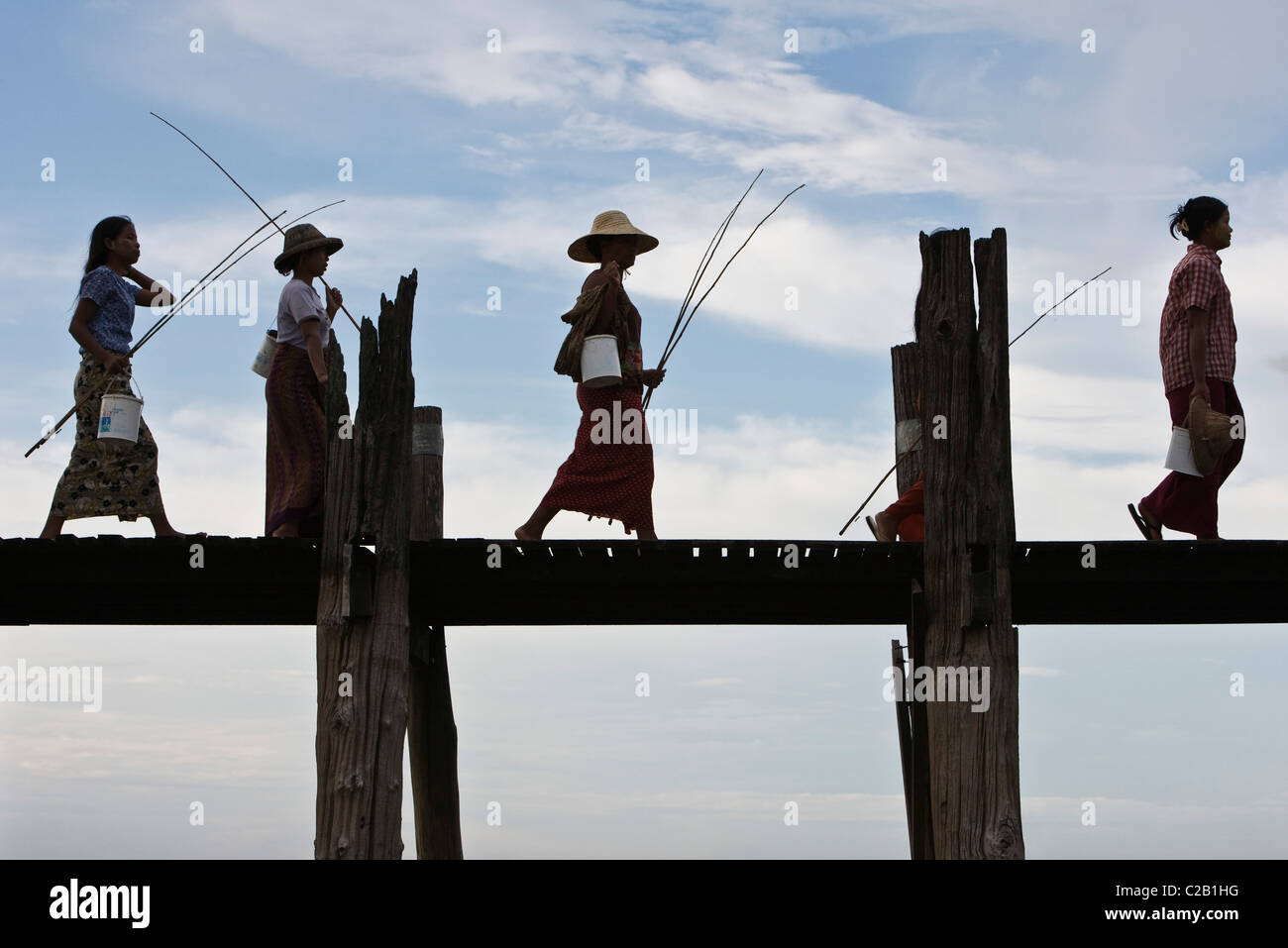 Amarapura, Myanmar, Frauen mit Angelruten und Eimer über U Bein Brücke zu Fuß Stockfoto