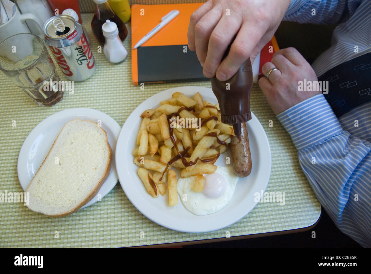 Braune Plastikflasche mit Würstchen, Ei und Pommes Frites und Weißbrot. Ganztägiges Frühstück, Mittagessen im Regency Cafe Westminster, Büroangestellter in Hemdärmeln Mittagsmahlzeit London SW1 UK. 2011 2010er Jahre HOMER SYKES Stockfoto