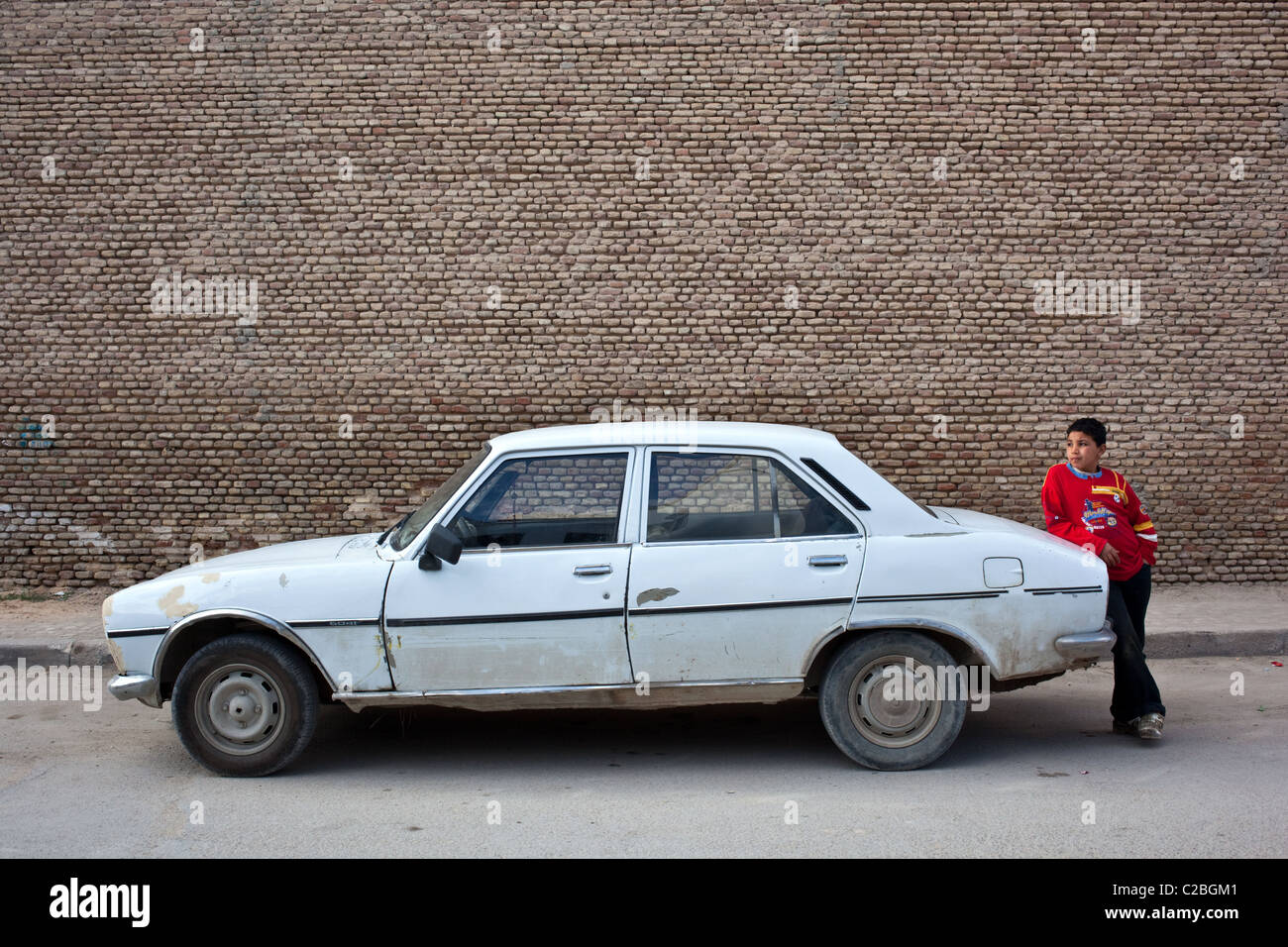 Ein kleiner Junge steht eine alte Peugeot 504 Auto in die Altstadt von der UNESCO gelistet Stadt Kairouan, Tunesien. Stockfoto
