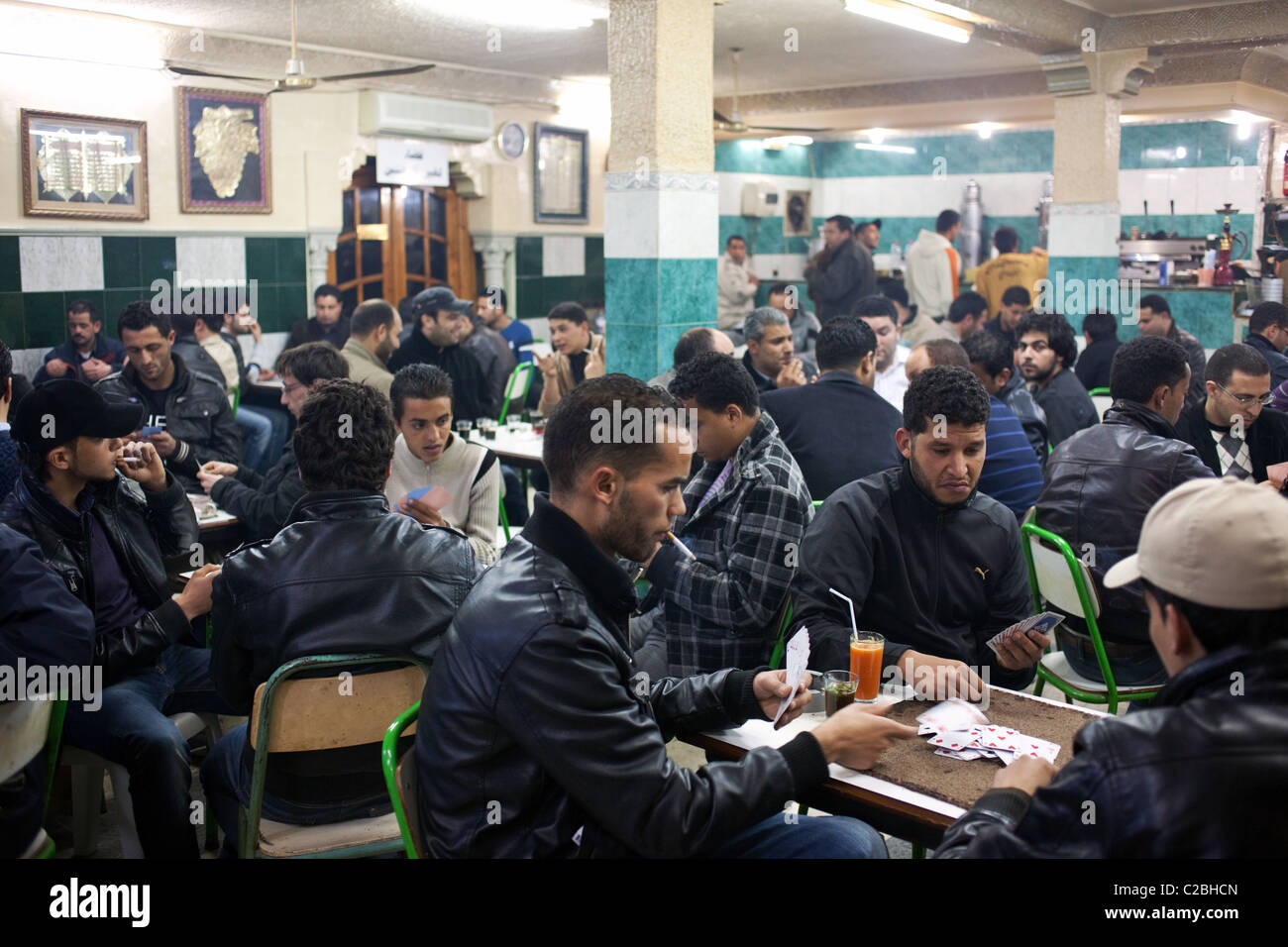 Männer spielen Karten, rauchen Zigaretten und Kaffee trinken in einem traditionellen Kaffeehaus in Kairouan, Tunesien. Stockfoto