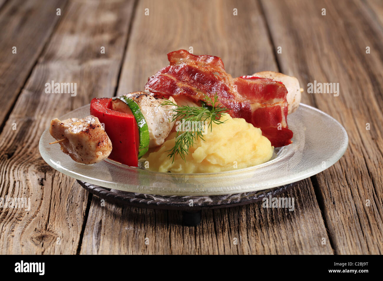 Huhn Schaschlik mit Stampfkartoffeln und Scheibe Speck Stockfoto