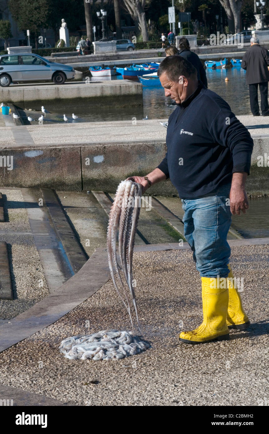 Fischer mit Toten Oktopus Fang fing Meeresfrüchte frisch Paul wichtige Seite Keyside gelb Whelly Stiefel Wellys Stockfoto