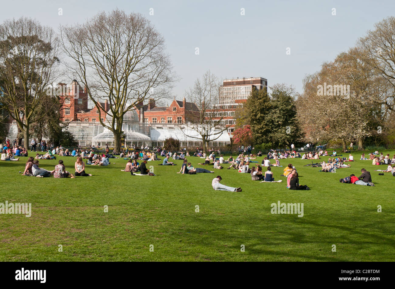 Kundenansturm auf dem Rasen außerhalb des viktorianischen Palmenhaus, botanischen Gärten, Belfast, während ein warmer Frühlingstag Stockfoto