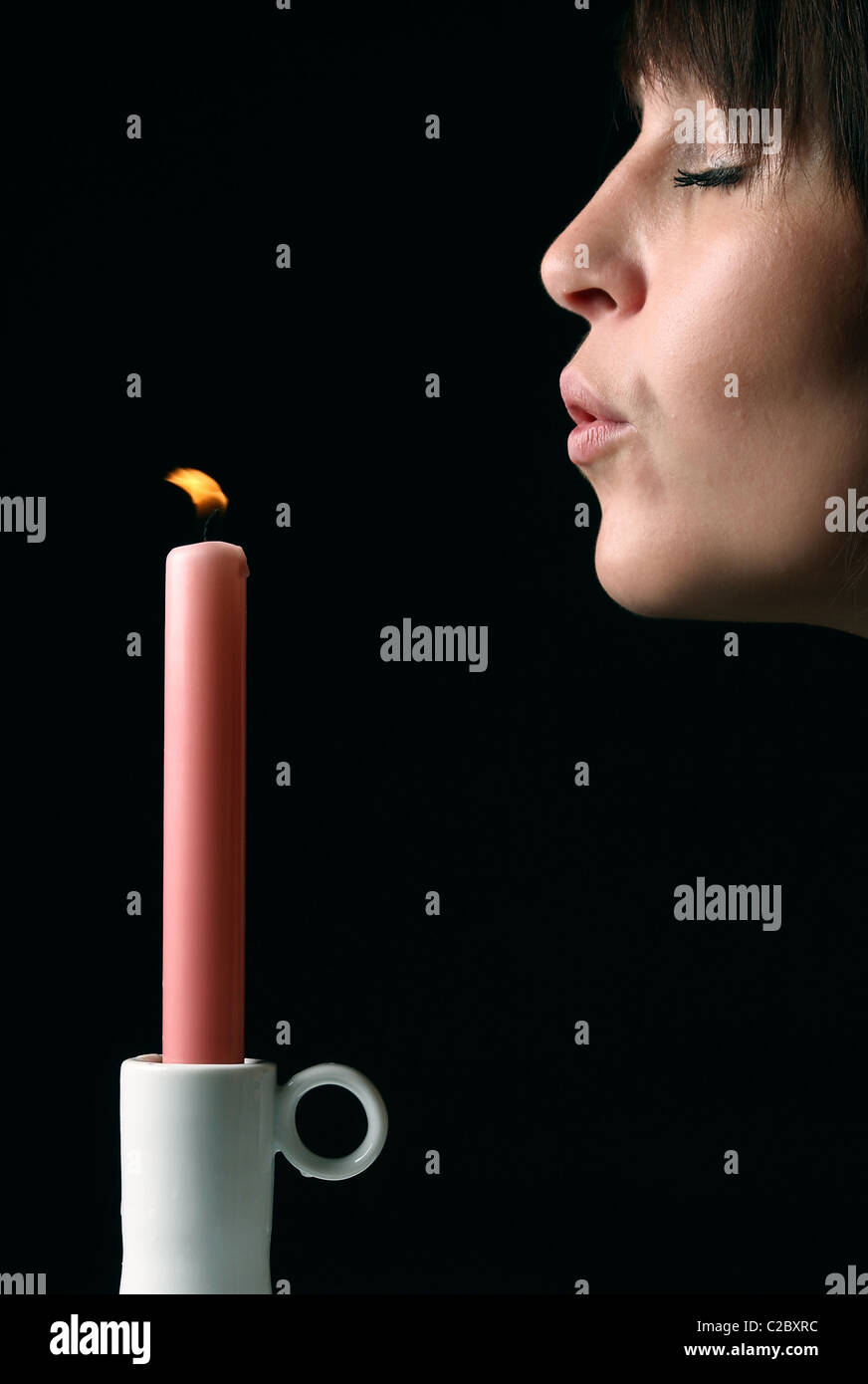 Eine junge Frau, die eine Kerze ausblasen Stockfoto