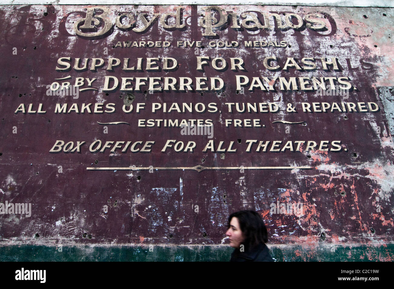 Eine alte bemalte Werbung [Geist Zeichen] für ein Klavier Lieferant mit einem Fußgänger. Dieses berühmte Geist Zeichen ist in Hackney, London. Stockfoto