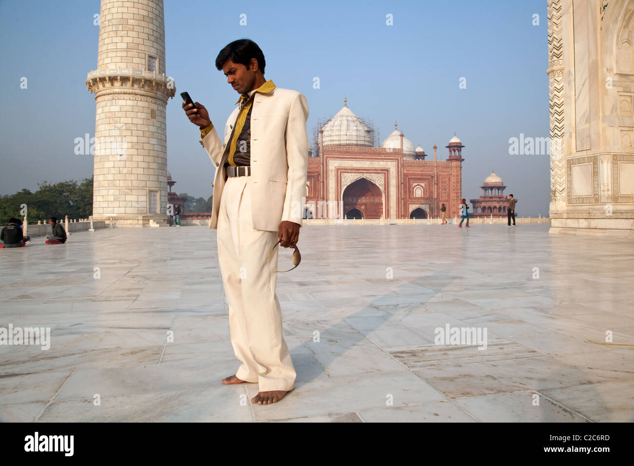 Eine junge indische Besucher in einem weißen Anzug mit einem Handy vor Taj Mahal in Agra, Indien. Stockfoto