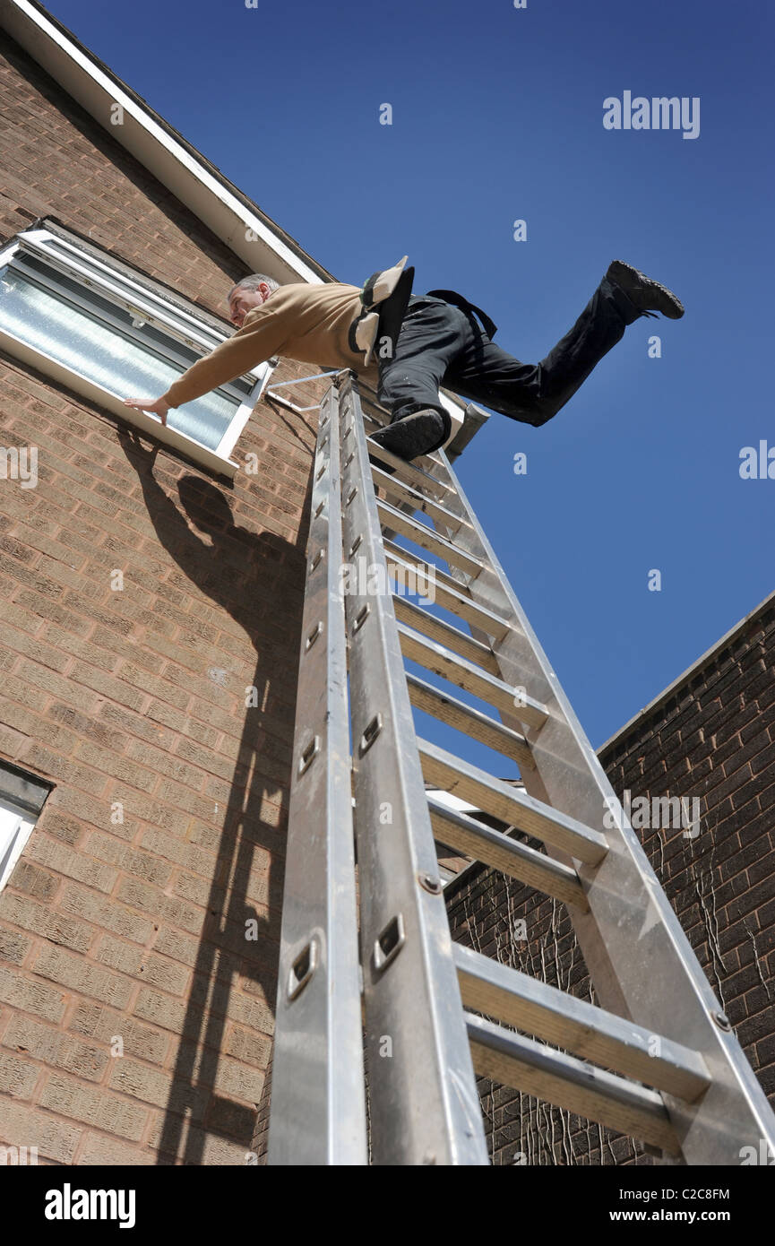 ARBEITER ÜBER BALANCIEREN AUF LEITERN ARBEITEN AM HAUS RE LEITER SICHERHEIT DIY-GESUNDHEIT UND SICHERHEIT GEFAHREN HERUNTERFALLEN BUILDER UK Stockfoto