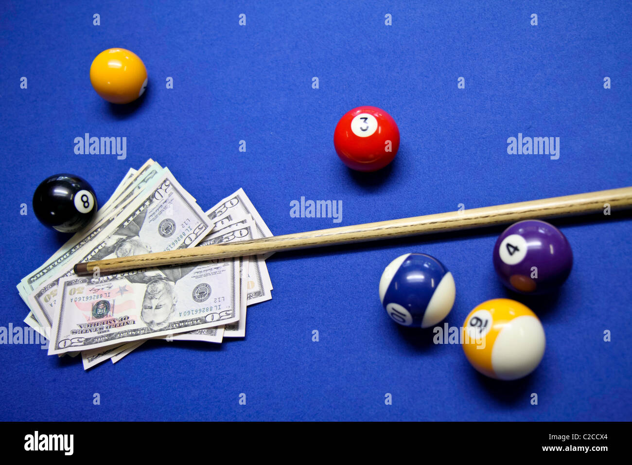 Pool-Queue und Kugeln mit US-Dollar auf einem Billardtisch Stockfoto