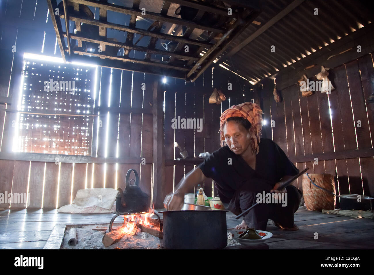 PA-O Indianerin in native Kostüm ist am offenen Kamin in ihrer Shanty-Küche kochen. Samkar, Inle-See, Shan-Staat, Burma. Stockfoto