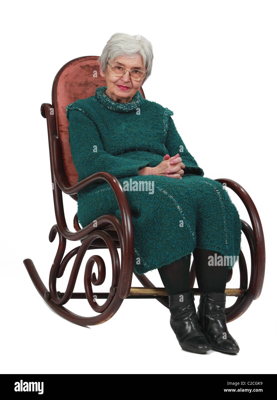 Alte Frau sitzt auf einem hölzernen Schaukelstuhl vor einem weißen Hintergrund isoliert. Stockfoto