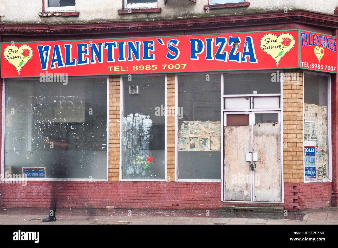 Eine verschwommene männliche Figur geht Valentine's Pizza Amhurst unterwegs in Hackney, London, derzeit geschlossen. Stockfoto