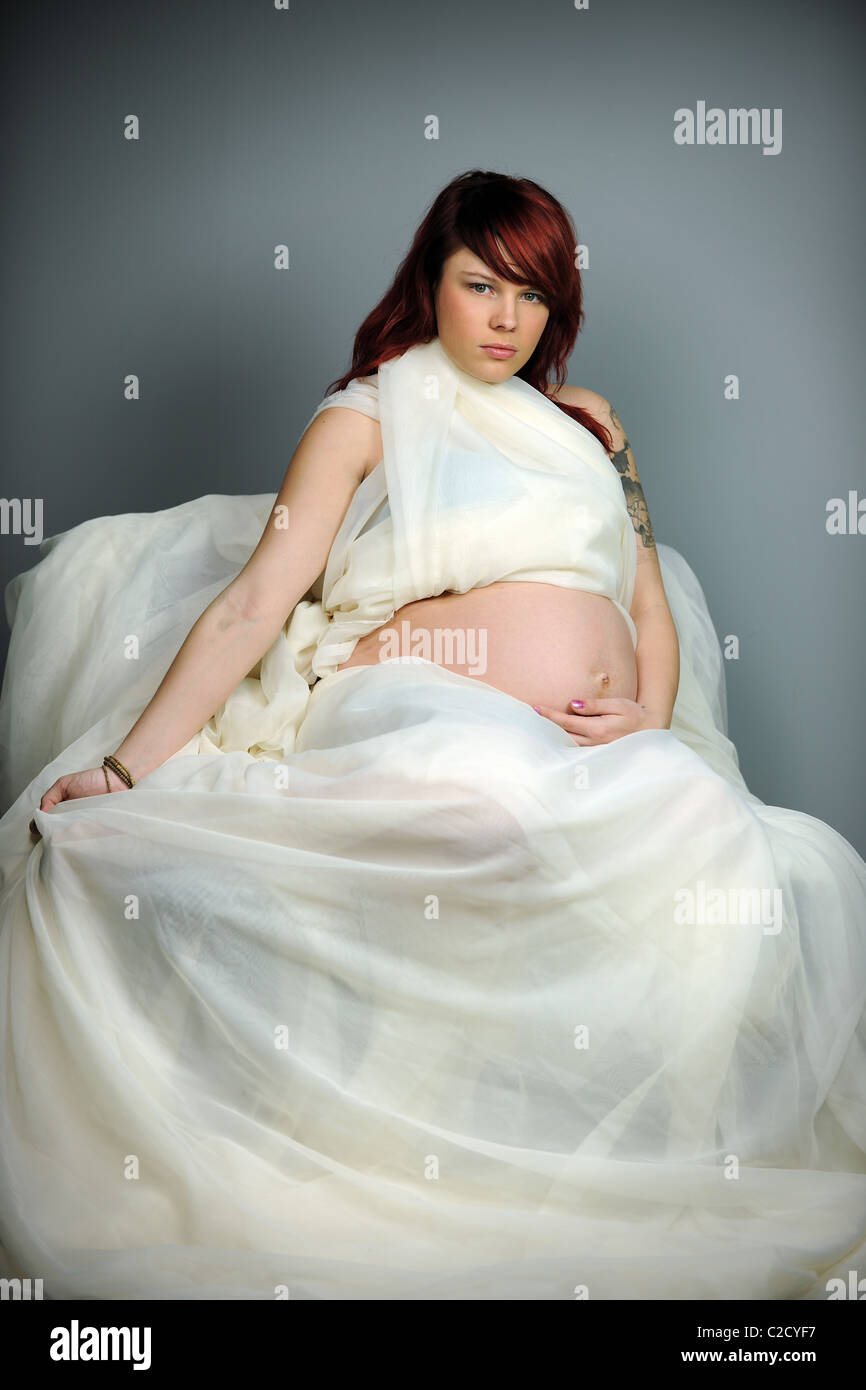 Porträt von schwangeren Frauen in weißer Kleidung auf neutralem Hintergrund Stockfoto
