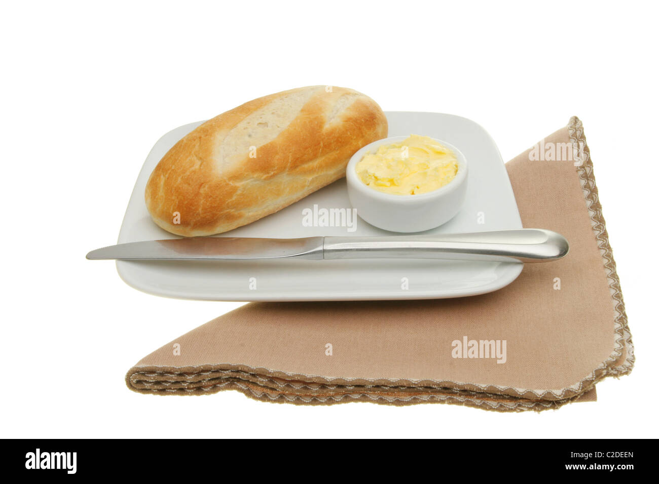 Baguette-Brötchen mit Butter und ein Messer auf einem Teller mit einer Serviette Stockfoto