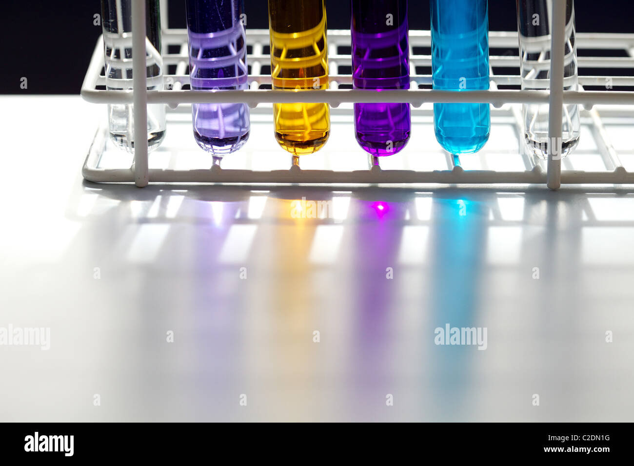 Rack mit sechs Reagenzgläsern in einem Labor mit Flüssigkeiten in verschiedenen Farben Stockfoto