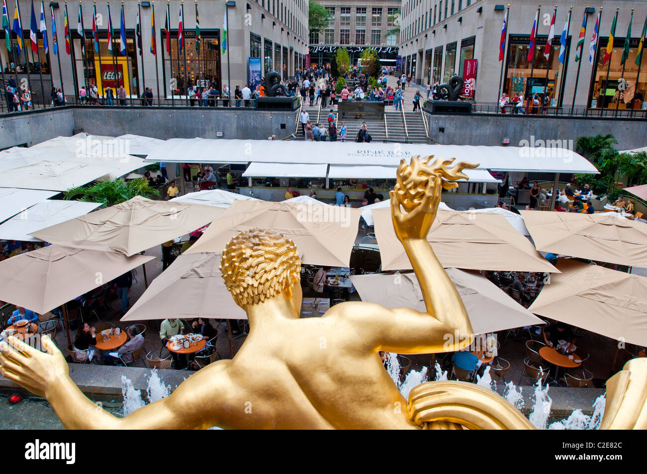 Goldener Prometheus-Skulptur blickte Luft Café Sonnenschirme am Rockefeller Center in Manhattan, New York City zu öffnen Stockfoto