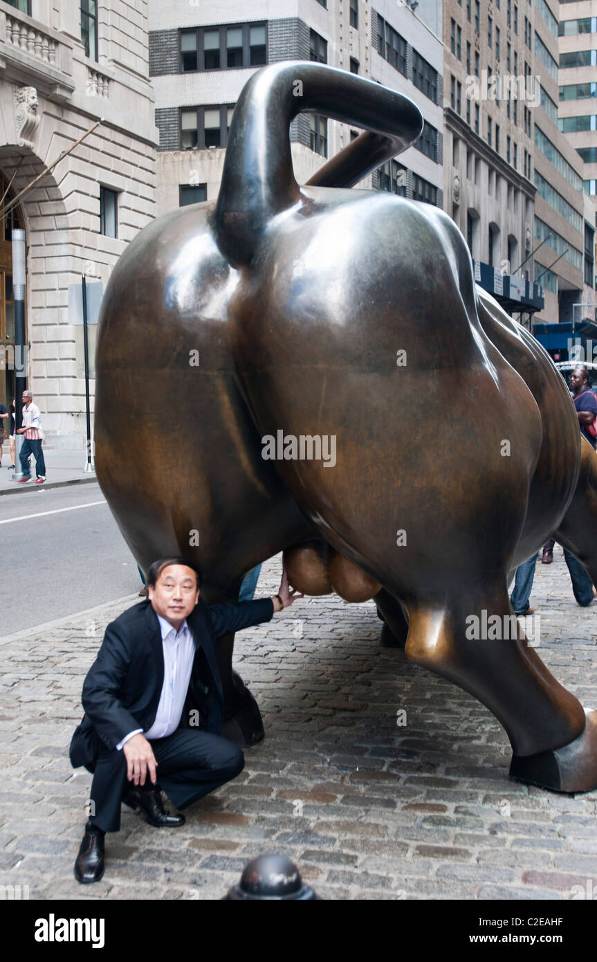 Asiatische Touristen berühren Hoden des Ladevorgangs Bull. Wall Street Bull oder Bowling Green Stier Bronze-Statue, Financial District Stockfoto
