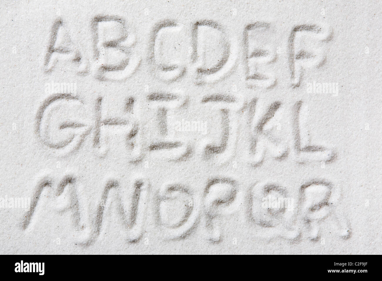 Ersten Halbjahr ein Großbuchstaben-Alphabet geschrieben im Sand - ein Designer-tool Stockfoto