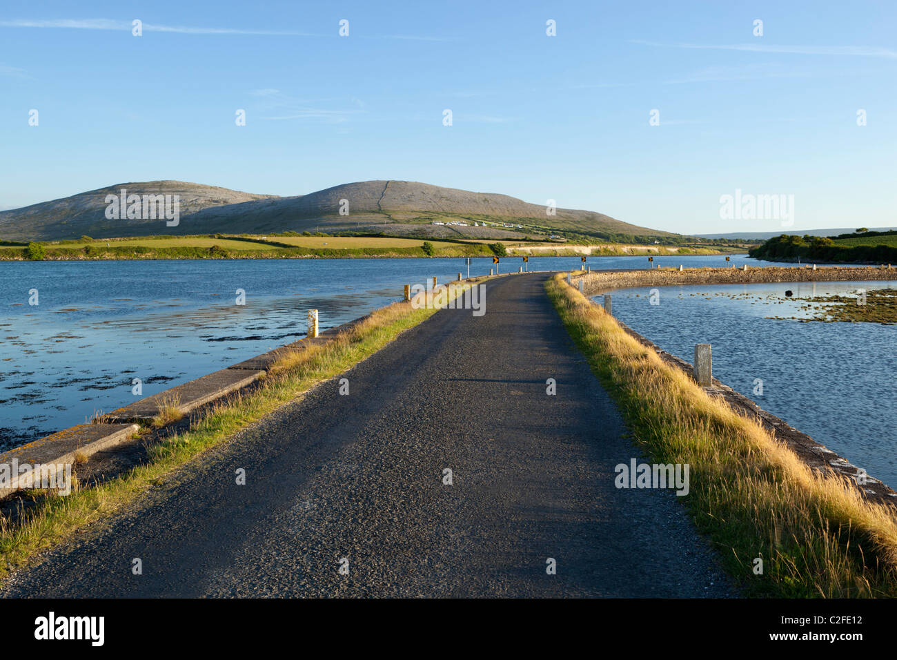 Empty road running below Burren mountains and Galway Bay Stockfoto