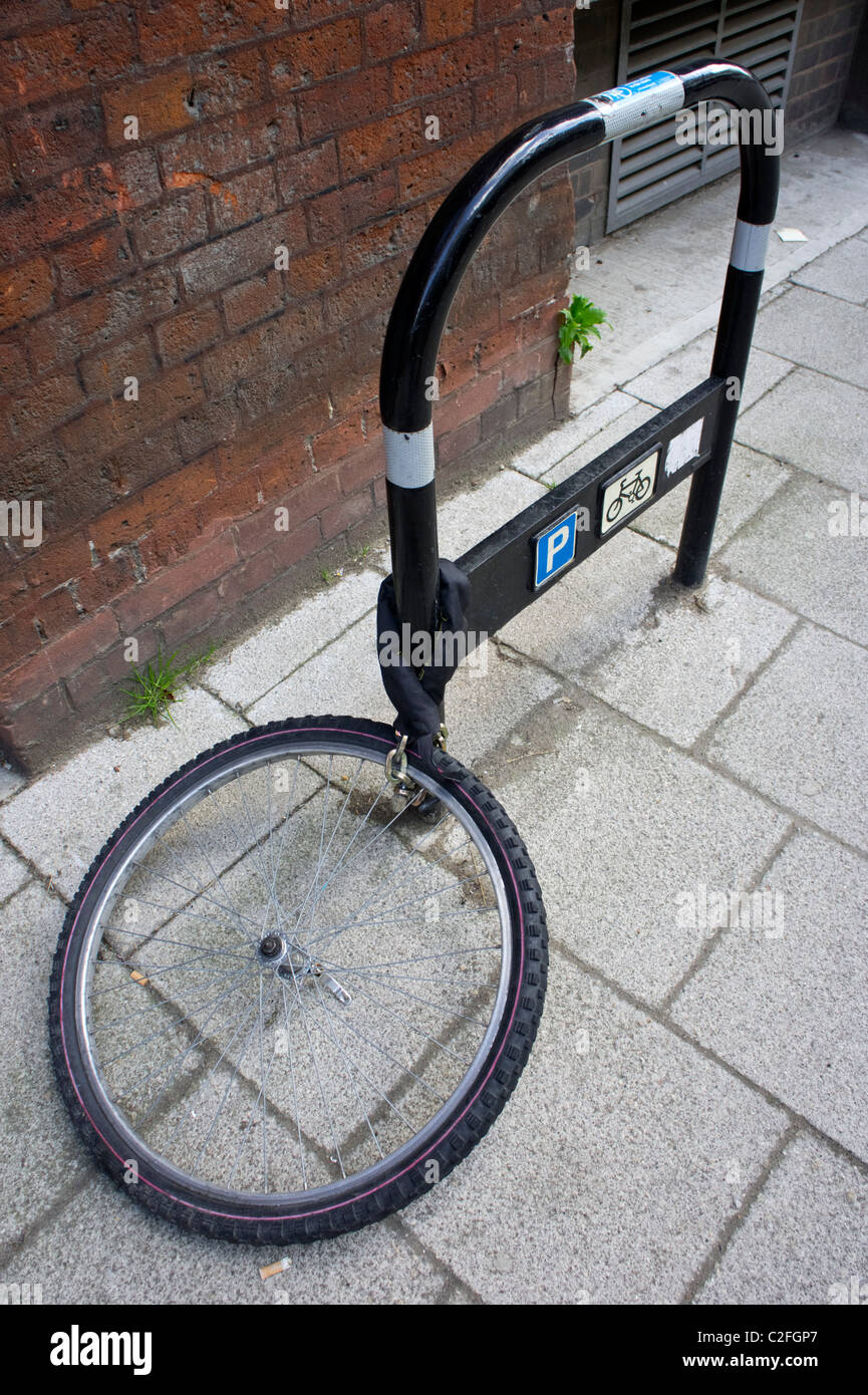 Fahrrad-Rad angekettet an einen Fahrrad-Parken post Stockfoto