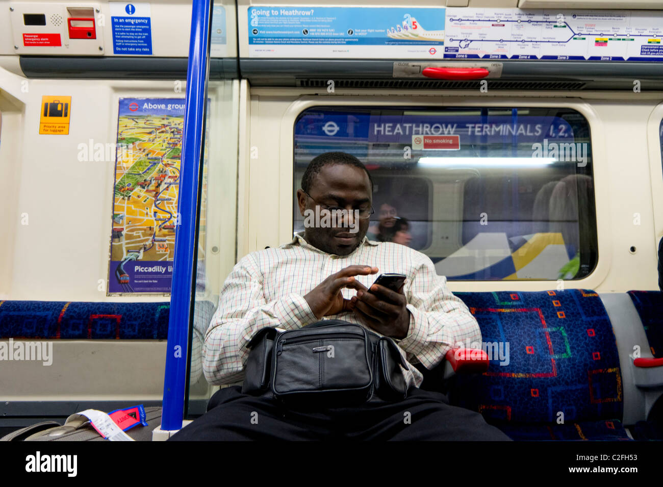 Schwarzer Mann nutzt sein Smartphone mit der Londoner U-Bahn Stockfoto