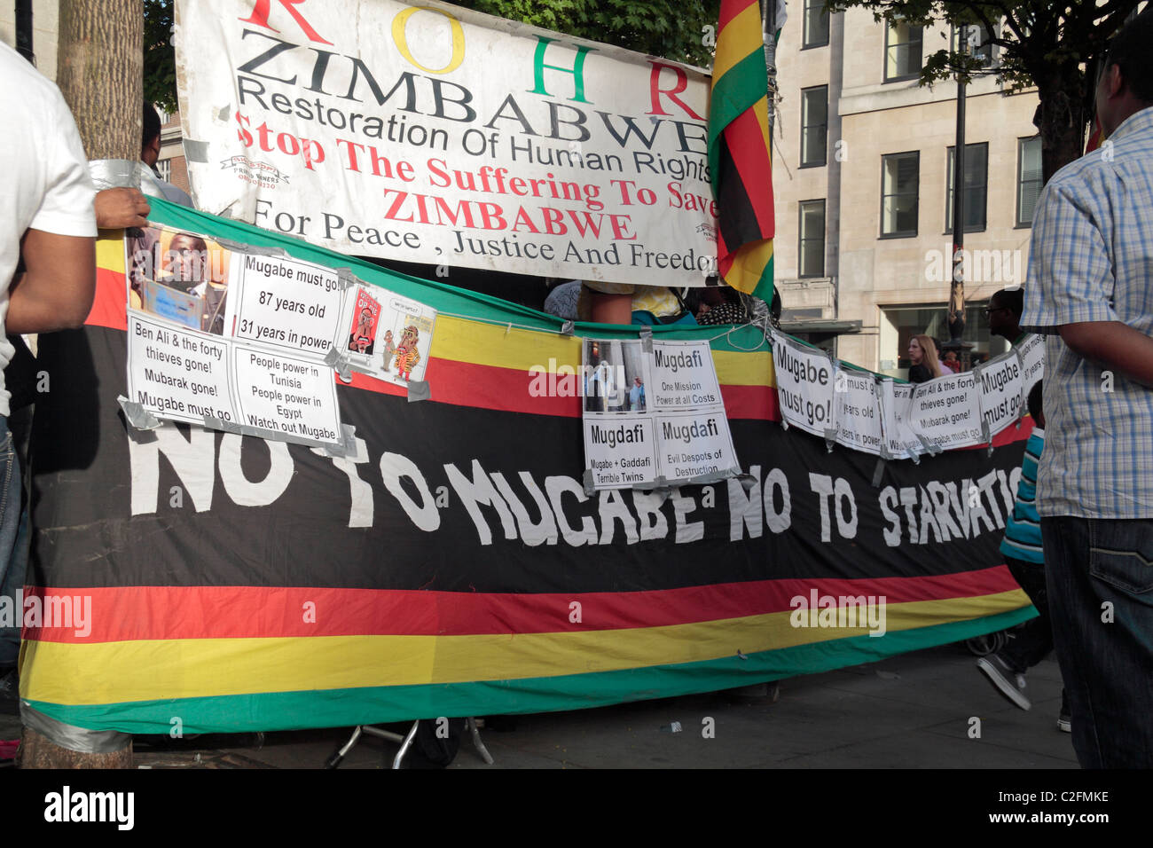 Große Banner am wöchentlichen Anti-Robert Mugabe Protest vor der Botschaft von Simbabwe am Strand, im Zentrum von London, UK. Stockfoto